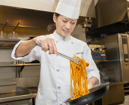 パスタを炒めているC.R.さん