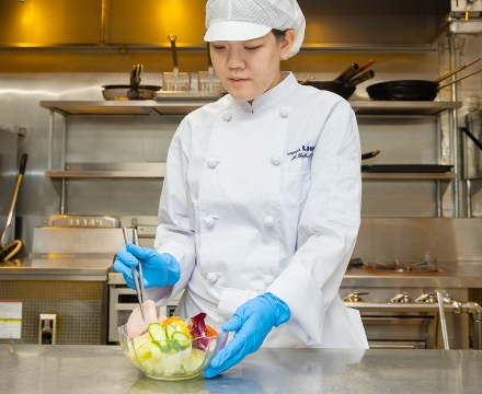 サラダを盛り付けているY.H.さん